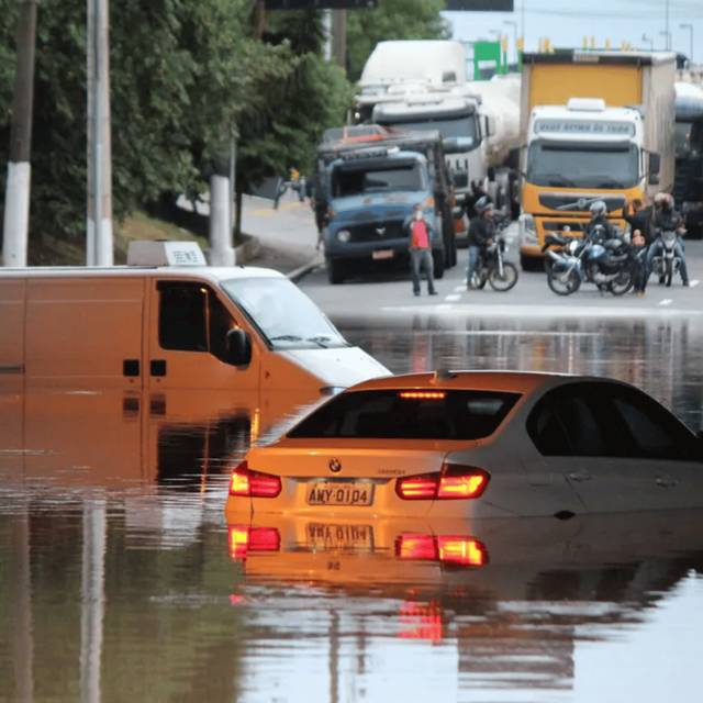 Avenida alagada com carros submersos e trânsito parado